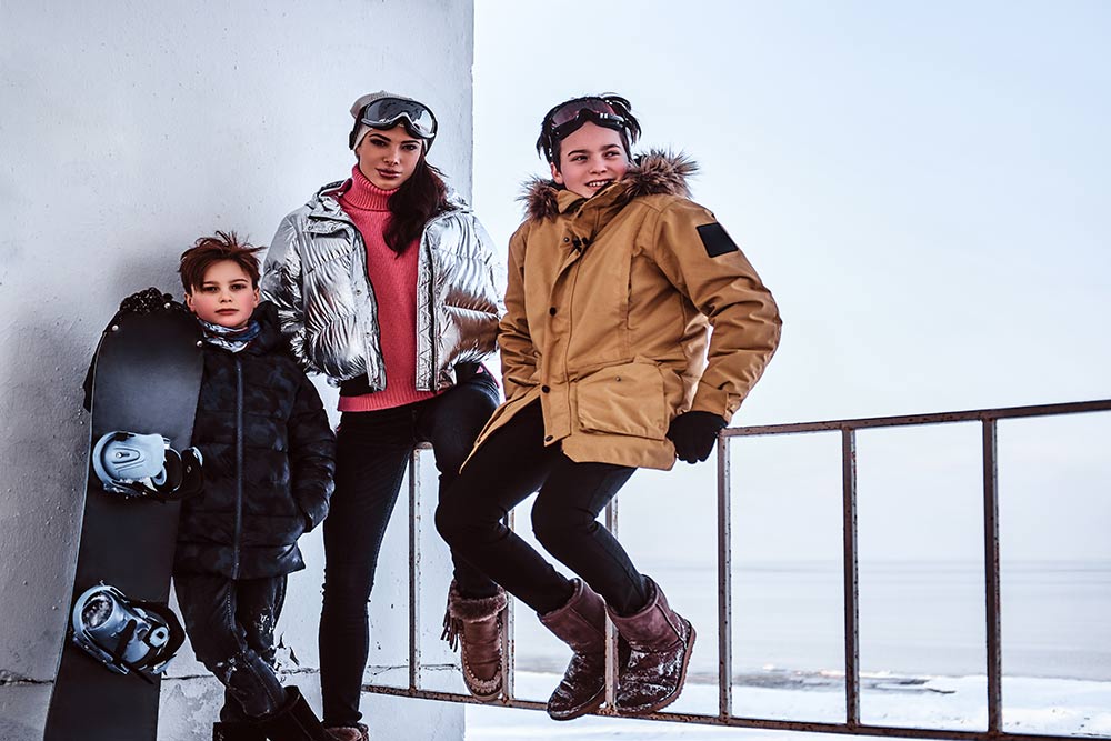 outdoor-activities-winter-holidays-family-wearing-stylish-clothes-posing-with-snowboard-railing-snowy-beach