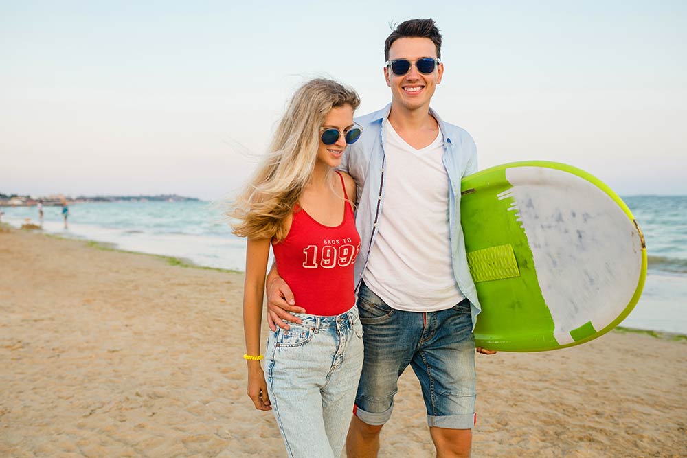 young-smiling-couple-having-fun-beach-walking-with-surf-board